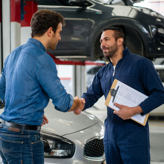 Man greeting a mechanic with a handshake at an auto repair shop