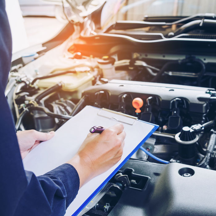 Mechanic holding clipboard and checking the car
